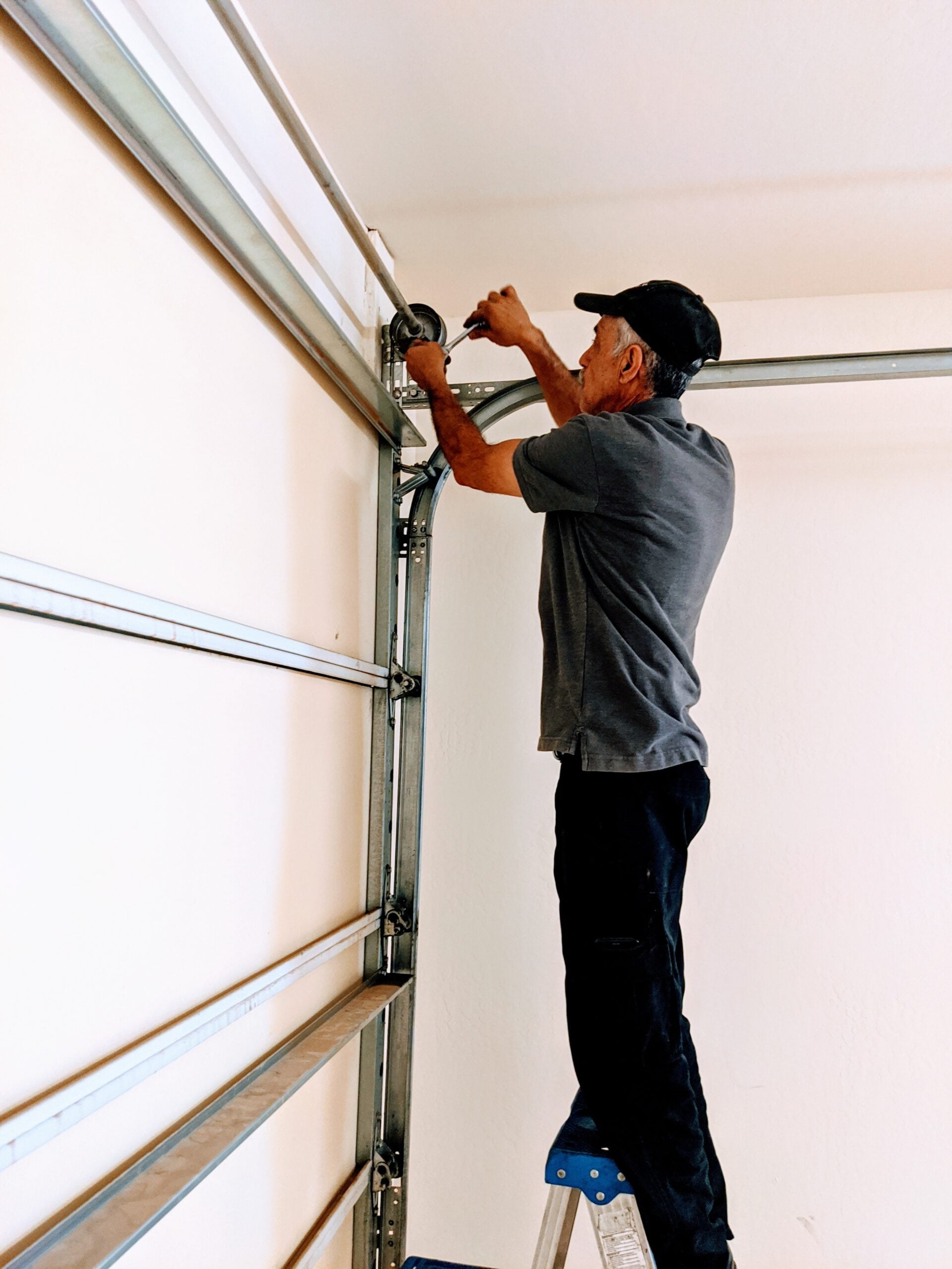 Professional garage door roller replacement and track repair service in Phoenix AZ with experienced technician performing residential overhead door maintenance and adjustments.