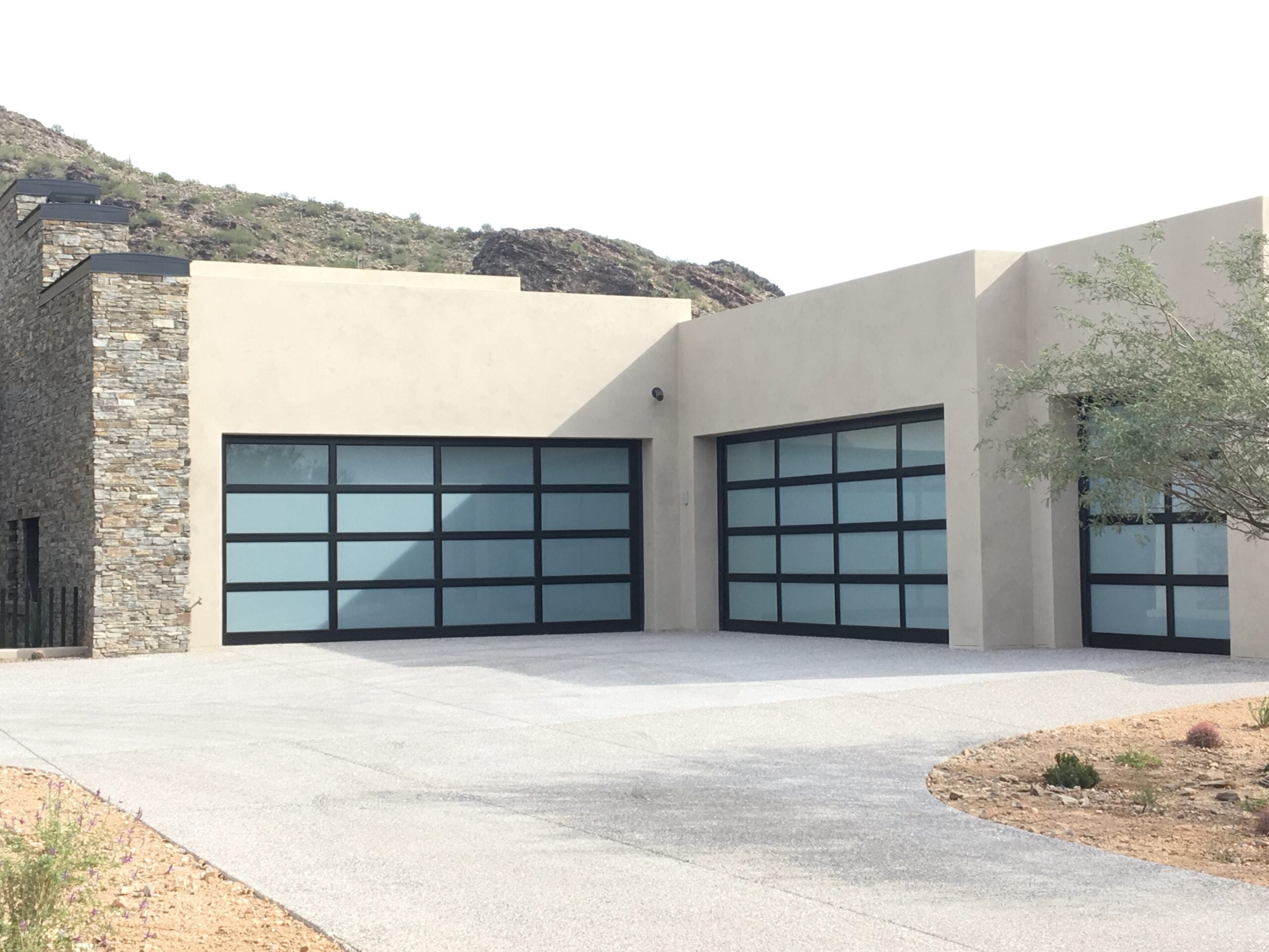 Modern glass garage door installation in Scottsdale AZ featuring full-view aluminum frame garage doors for luxury contemporary desert homes.